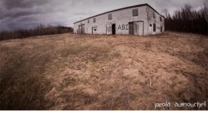 Abandoned building in field surrounded by a forest